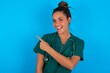 beautiful doctor woman wearing medical uniform over blue background glad cheery demonstrating copy space look novelty