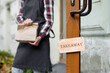 woman holds a wooden sign with the inscription takeaway, open or closed at the door of a restaurant or coffee shop. the working hours of the restaurant or the food and beverage delivery service. to