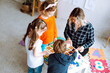 © Татьяна Волкова - Top view of group of preschoolers and teacher. Young woman showing how to play board games collecting geometric figures.