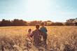 © kieferpix - Fatherhood, and family parenting concept. Father and his children spending time together in nature field looking out to the sunset view.