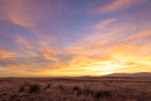 Vivid Yellow Sunrise Over Dry Grassy Plains With Distant Mountains At Sunrise