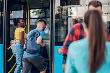Multiracial Friends Entering A Public Transport At A Bus Stop