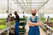 © DC Studio - Portrait of smiling man in greenhouse with hydroponics enviroment with engineers using laptop controlling irrigation system. Caucasian farmer posing happy in organic crops and vegetables farm.