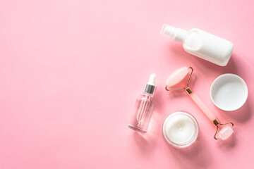 Poster - Natural cosmetics on pink. Skin care product, cream, soap serum, jade roller. Flat lay image with copy space.