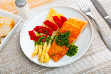 Wall Mural - Appetizing Roasted salmon steak with asparagus, pepper and herbs in a cafe