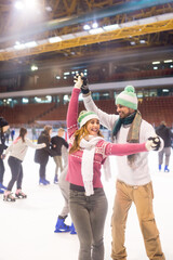 Young couple ice skating in the public ice skating rink in winter