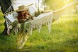 Woman with hat resting in comfortable hammock at green garden.