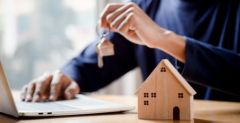 Wall Mural - Businessman choosing mini wood house model from model and row of coin money on wood table, selective focus, Planning to buy property. Choose what's the best.