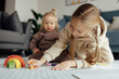 © Алина Бузунова - Little caucasian siblings drawing together on floor in living room at home. Happy girl eight years old and her baby sister painting with crayons. Art and crafts for toddler and preschooler