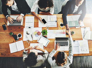 Aufkleber - Handshake greeting before a business meeting proposal of collaboration and teamwork. Above view of creative office team and marketing agents working on graphs, data and information