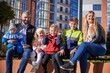 © anatoliy_gleb - Two adults spending time with cute children, smiling in spring sunny day. Front view of middle-aged parents sitting on bench with four adorable kids, having rest in city centre. Concept of family.