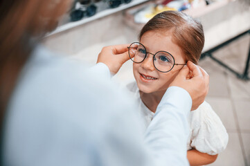 Wearing new eyewear. Woman and girl is in the glasses store