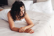 © Надежда Филатова - Woman with wet curly hair laying on a bed and looking down. Romantic sad mood