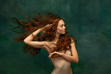 adorable tender redhead girl with long curly hair isolated over dark green background. fabolous curl
