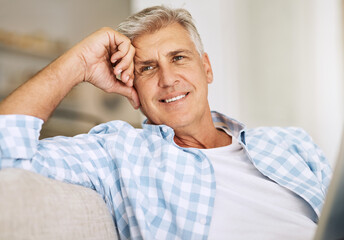 Poster - Handsome mature man relaxing on a sofa, casual, carefree and happy at home. Senior male enjoying the pleasure of retired life, satisfied and stressless. Older guy thinking, smiling and daydreaming