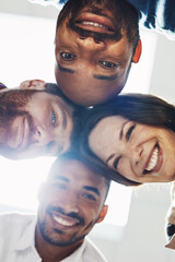 Aufkleber - Portrait of a diverse group of happy office workers from below joining together in a huddle for support and unity with lights in the background. Cheerful motivated colleagues ready for business