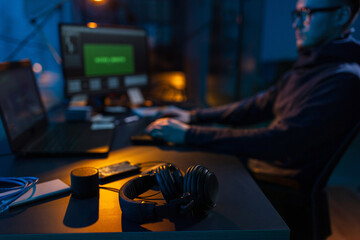 Poster - cybercrime, hacking and technology concept - close up of male hacker in dark room writing code or using computer virus program for cyber attack