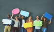 © Tamani Chithambo/peopleimages.com - Smiling casual team of diverse people holding opinion speech bubbles, to voice their important communication message. Creative group standing with colorful copyspace sign boards together in a row