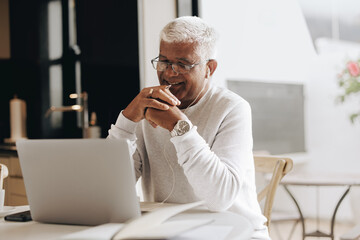 Wall Mural - Happy senior businessman attending an online meeting at home