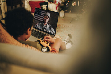 Wall Mural - Little boy video calling his military father at Christmas