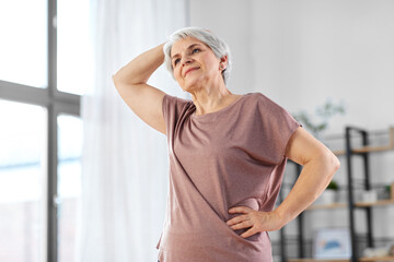 Canvas Print - sport, fitness and healthy lifestyle concept - smiling senior woman exercising at home