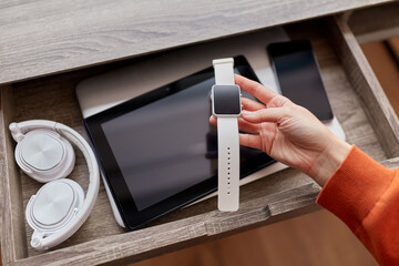 digital detox and technology concept - close up of hand holding smart watch and different gadgets in