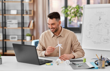 Canvas Print - distance education, school and green energy concept - happy smiling male teacher with laptop computer and wind turbine model having online class at home office