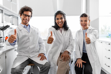 science, work and people concept - international group of happy scientists showing thumbs up in laboratory