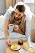 © Syda Productions - health, illness and people concept - sick man drinking hot tea with lemon and honey in bed at home