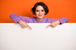 Photo of funky shiny girl dressed purple pullover pointing white placard empty space isolated orange color background
