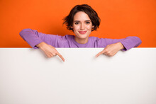 Photo Of Funky Shiny Girl Dressed Purple Pullover Pointing White Placard Empty Space Isolated Orange Color Background