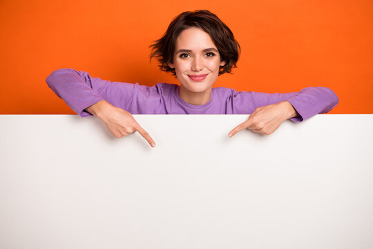 photo of funky shiny girl dressed purple pullover pointing white placard empty space isolated orange
