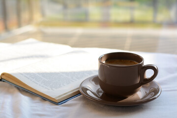 Aromatic morning coffee and open book on bed indoors