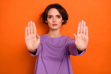 Canvas Print - Photo of serious confident girl dressed purple pullover showing arms stop isolated orange color background