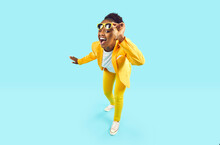 Full Body Happy Cheerful Afro American Woman Wearing Stylish Yellow Suit And Trendy Glasses Standing Isolated On Blue Background, Looking At Camera, Winking Her Eye And Smiling. Party, Fashion Concept
