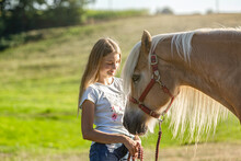 Girls And Horses: Portrait Of A Teenager Girl And Her Haflinger Pony Interacting Together. A Young Female Equestrian Cuddle With Her Horse In Summer Outdoors