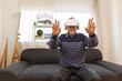 © anon - Senior man using VR headset to explore augmented reality at home in living room . Disabled elderly male playing virtual online game, having fun with modern technologies.