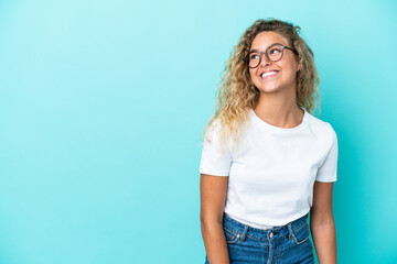 Wall Mural - Girl with curly hair isolated on blue background thinking an idea while looking up