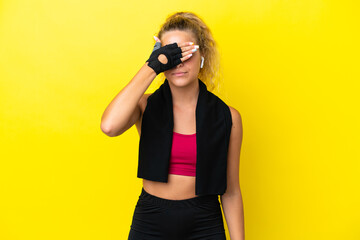 Wall Mural - Sport woman with towel isolated on yellow background covering eyes by hands. Do not want to see something