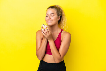 Wall Mural - Girl with curly hair isolated on yellow background holding a donut