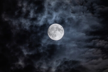 full moon at night. the illuminated face of the moon is wrapped in a cloud cover that covers it in a