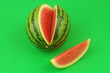 Leinwandbild Motiv Watermelon and one watermelon slice on green background