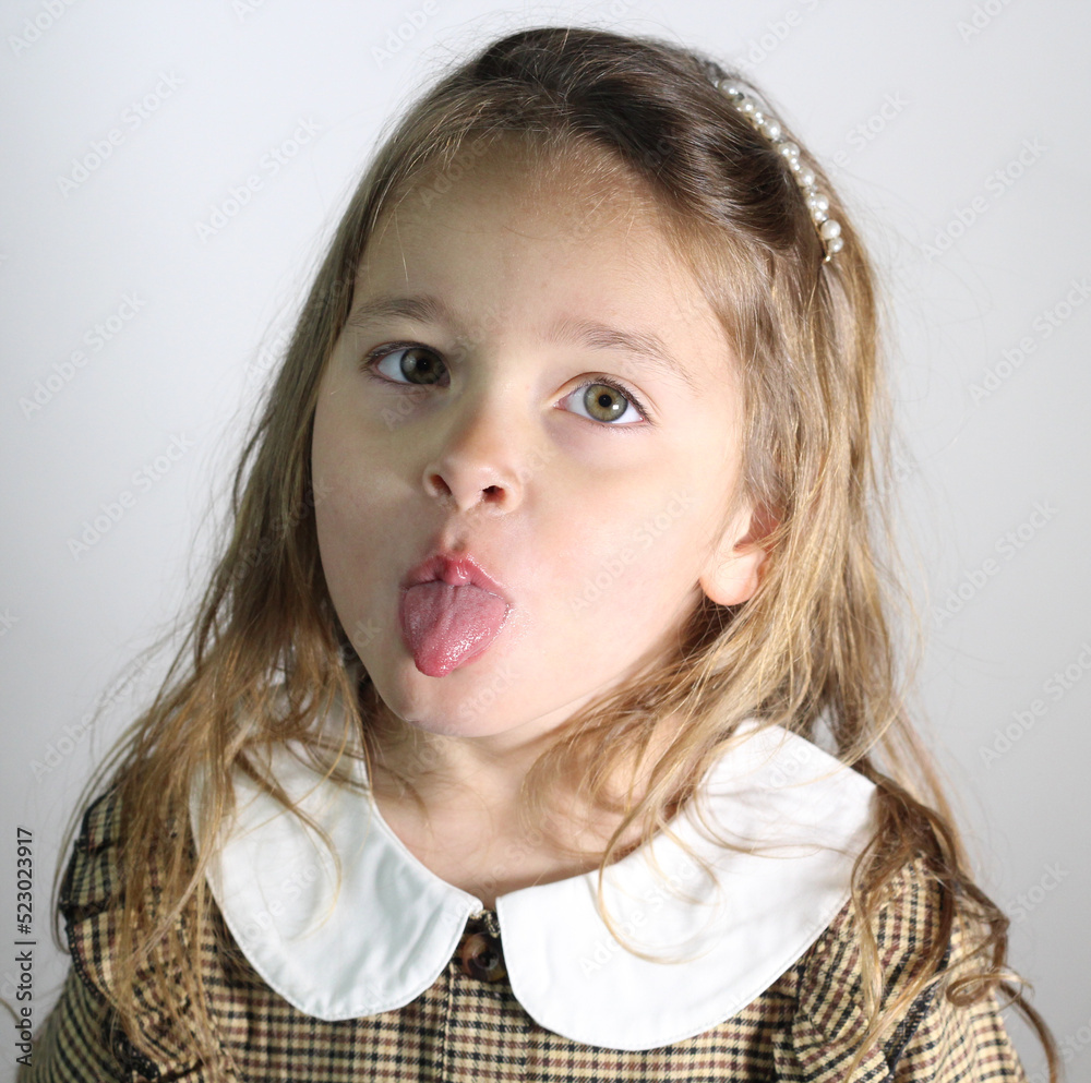 Cheerful little girl puts out the tongue on white background Stock ...