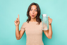 Young Hispanic Woman Holding A Water Of Jar Isolated On Blue Background Having Some Great Idea, Concept Of Creativity.