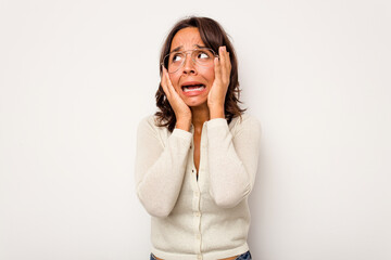 Wall Mural - Young hispanic woman isolated on white background covering ears with hands trying not to hear too loud sound.