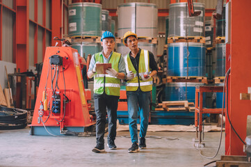 Asian engineer factory manager and mechanic worker employee in safety hard hat talking and inspection inside the factory