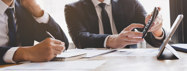 Business meeting, two caucasian, asian yong group man brainstorm analyzing on graph data of cost plan or document, paperwork and discussing in board room on table. People working conference room.