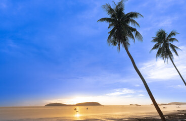 Sunrise in front of the beach with 2 coconut trees in the foreground.