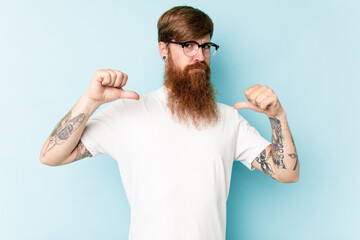 Young caucasian red-haired man isolated on blue background feels proud and self confident, example to follow.