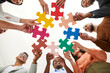 © Studio Romantic - Diverse multiracial multi ethnic team of happy smiling adult men and women holding colorful jigsaw puzzle parts, bottom view, from below. Modern business, teamwork, education, innovative ideas concept